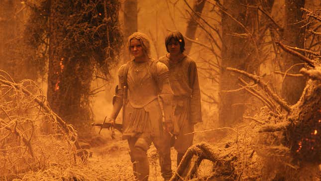 Galadriel and Theo walk through an ash-covered forest. 